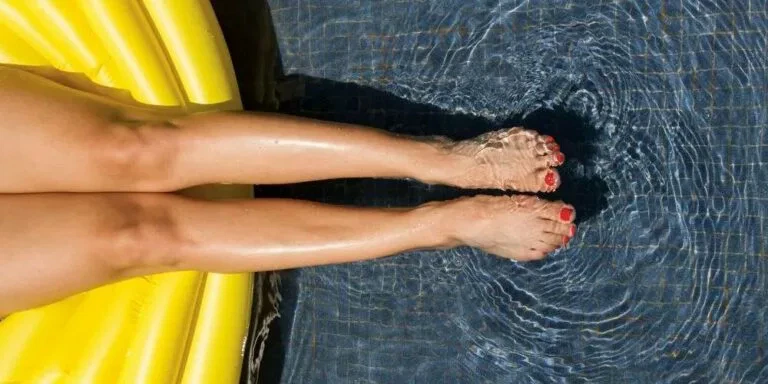 Jambes d'une femme parfaitement épiler au laser définitif dans une piscine au soleil