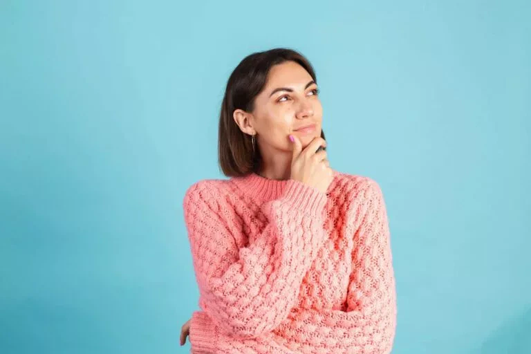 femme brune avec un pull rose qui réfléchit